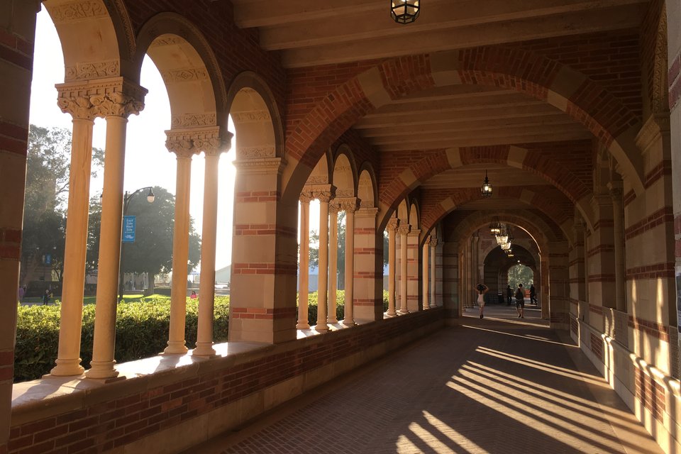 The sun casts a shadow through arches and columns and onto a walkway.